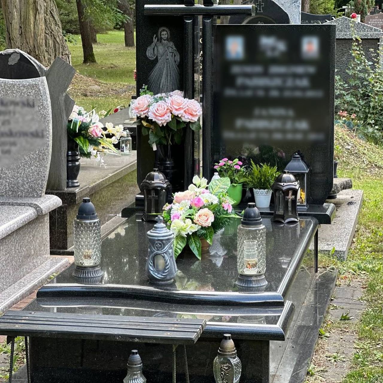 Kwiaty w wazonie, bukiet i znicze przy ciemnej tablicy nagrobnej — archiwum GRAAL