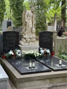 Stare nagrobki na cmentarzu z klasyczną symboliką: czaszka, księga i kwiaty