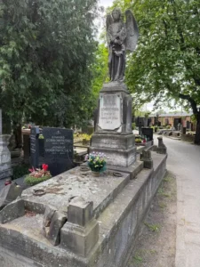 Stare nagrobki na cmentarzu z aniołem trzymającym wieniec i cmentarnym murem w tle