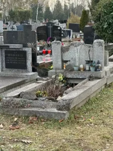 Pomnik z lastryko w stanie ruiny, z rozsypanymi elementami wokół grobu