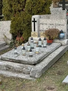 Pomnik z lastryko z wyraźnymi tabliczkami imiennymi, czarnym krzyżem i lampionami