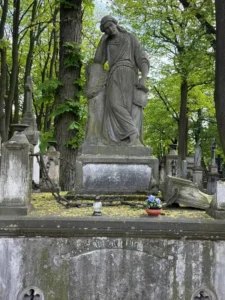Stare nagrobki na cmentarzu z rzeźbą kobiety opierającej głowę na kolumnie z wieńcem