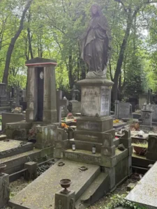 Stare nagrobki na cmentarzu z figurą Maryi stojącą na postumencie z napisem