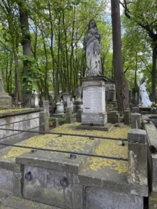Stare nagrobki na cmentarzu z monumentalną figurą Matki Boskiej na wysokim postumencie