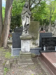 Stare polskie nagrobki na cmentarzu z figurą Matki Boskiej i marmurowym cokołem