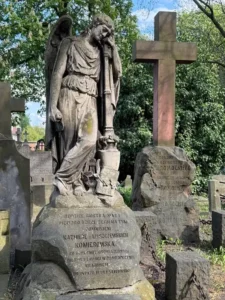 Stare nagrobki na cmentarzu z rzeźbą anioła wspierającego się na kolumnie w zadumie