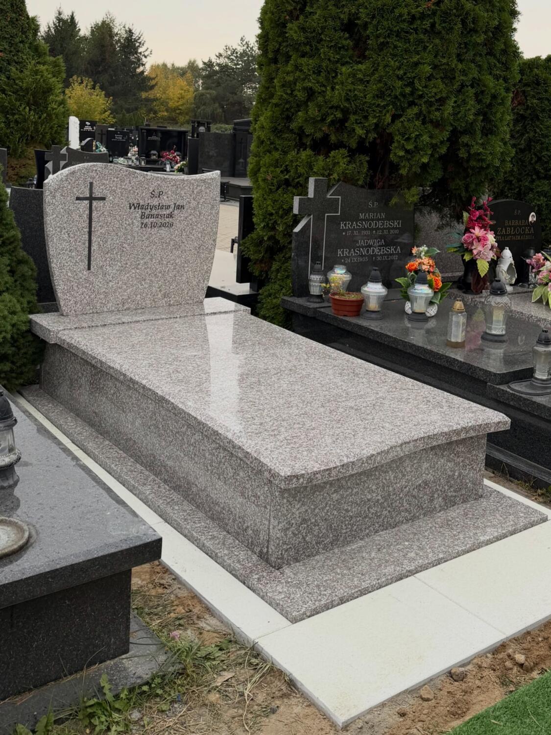 Jasna wzorzysta tablica GRAAL z krzyżem, ciemnym napisem i odbiciem światła na płycie