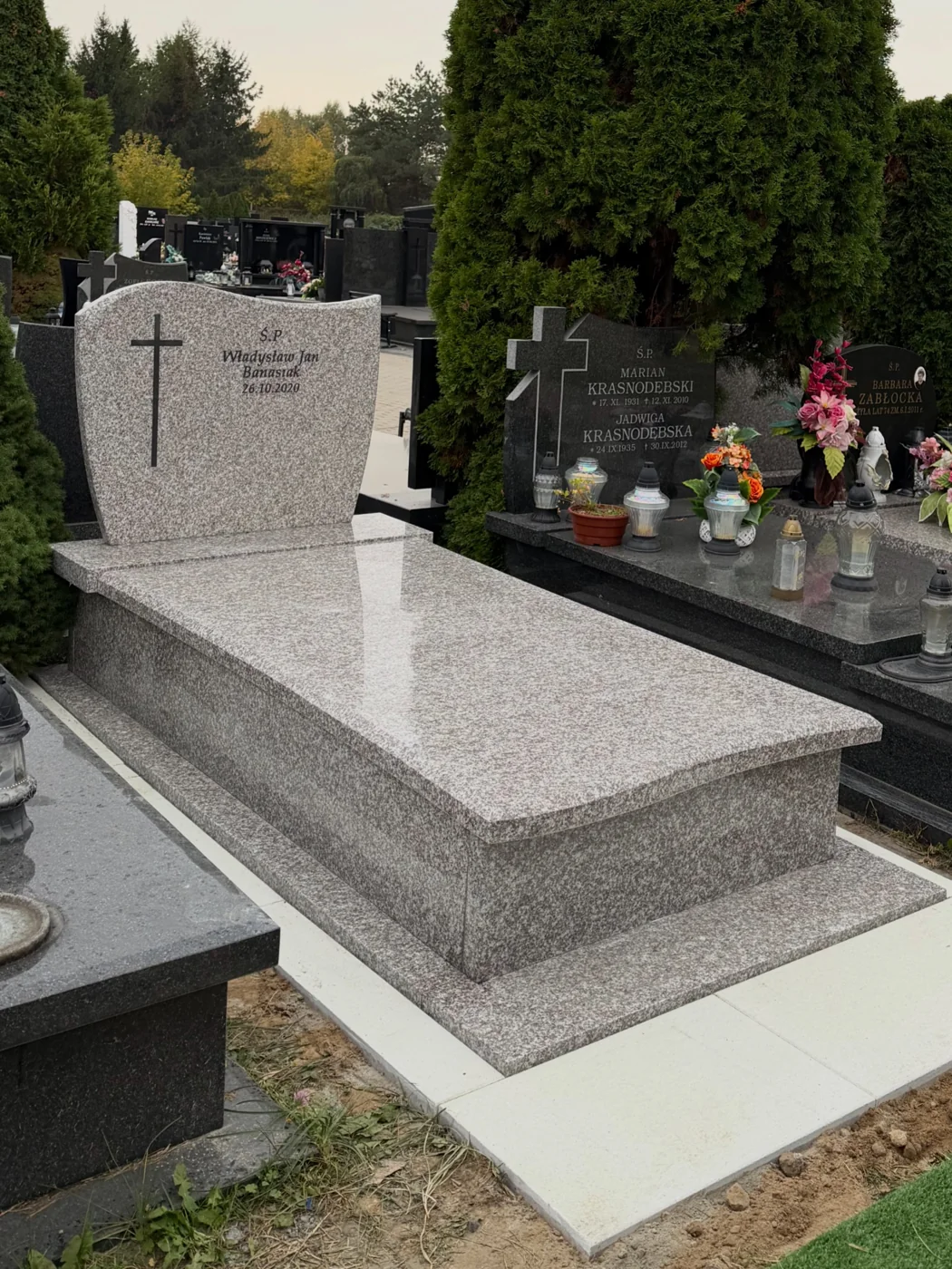 Jasna ziarnista tablica z ciemnym krzyżem i napisem oraz dopasowaną płytą nagrobka GRAAL