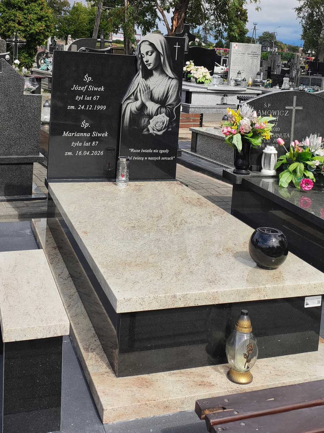 Ciemna tablica GRAAL z napisem i postacią religijną nad jasną poziomą płytą