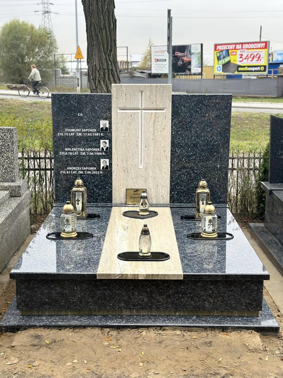 Nagrobek podwójny z dwiema ciemnymi tablicami po bokach jasnego centralnego panelu z krzyżem
