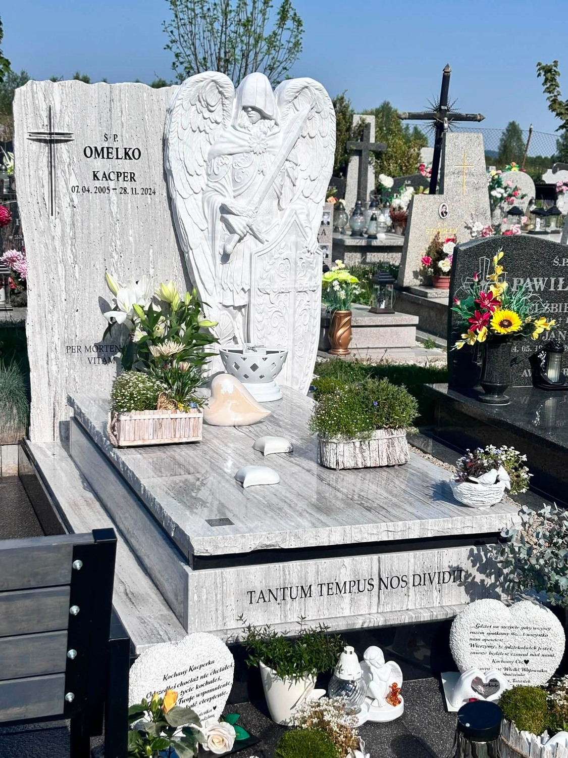 Jasna tablica z napisem i duża rzeźbiona postać ze skrzydłami i mieczem — realizacja GRAAL