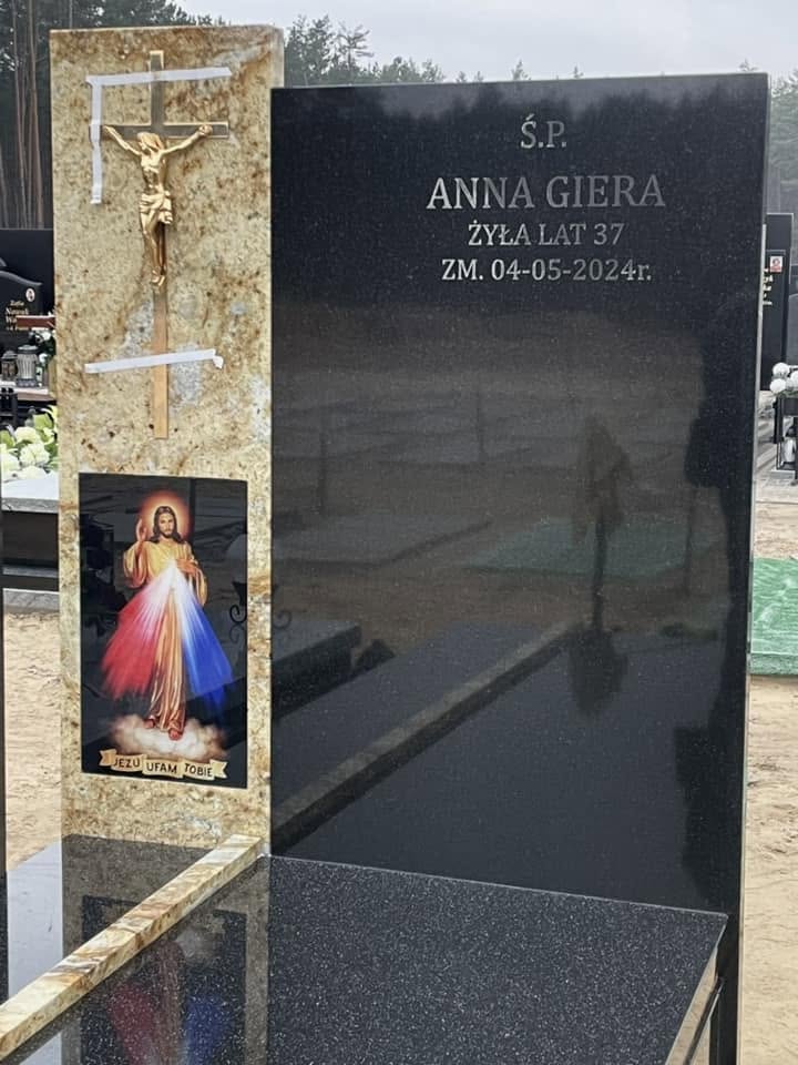 Szklany wizerunek Jezusa Miłosiernego na jasnym pasie granitu obok ciemnej tablicy nagrobka GRAAL