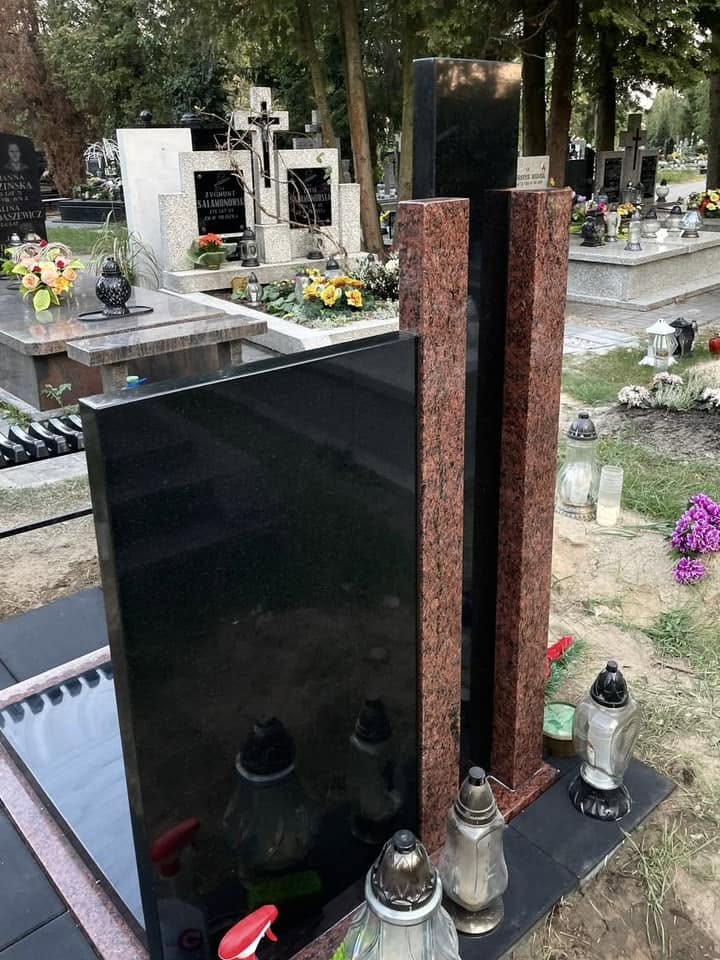 Tył tego samego nagrobka urnowego GRAAL: ciemna tablica bez napisów na widocznej tylnej powierzchni i czerwone pasy przy wysokim elemencie