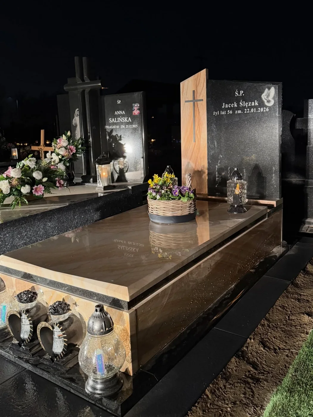 Nocna fotografia nagrobka GRAAL z jasną płytą, ciemną tablicą i grawerem gołębia